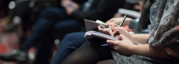 photo of a person writing in a notebook placed on their lap. 