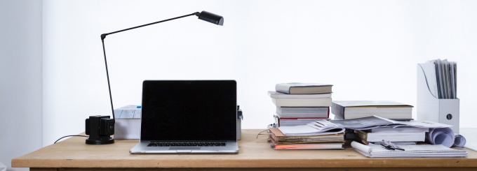 photo of a desk with a lamp and laptop and several books.