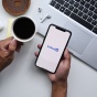 A person holding a phone with LinkedIn on it and a cup of coffee. 