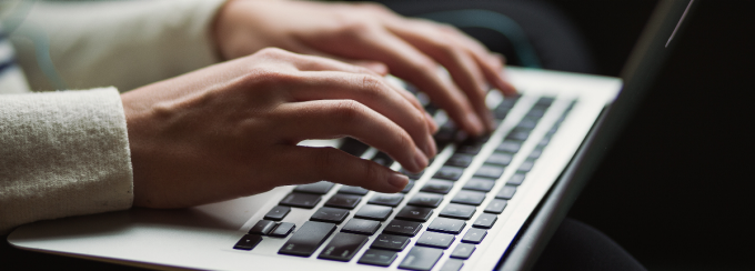 hands resting on a laptop keyboard. 