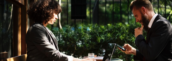 Photo a woman and man dressed in suits sitting outside at a park doing work on a laptop. 