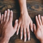 table top with 5 hands of varying skin color. 