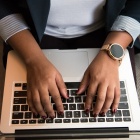 woman typing on a laptop that is resting on her lap. 