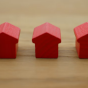 table top with 5 small wooden houses lined up in a row. 