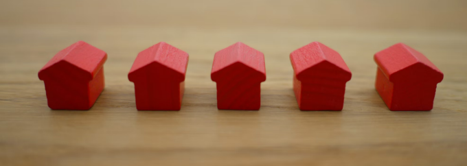 table top with 5 small wooden houses lined up in a row. 