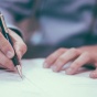 man filling out papers on a desk. 