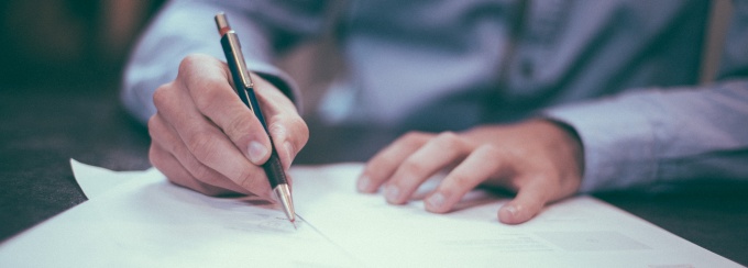 man filling out papers on a desk. 