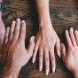 many diverse hands on a table. 