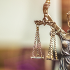 image of lady justice statue holding up a scale, books in the background. 