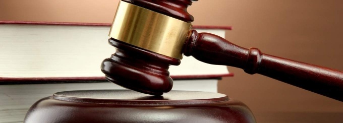 wooden gavel in front of books on a desk. 