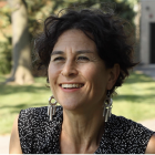 Irus Braverman, siming, outside wearing black and white spotted top, long earrings. 