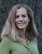 woman smiling, standing outside wearing green top. 