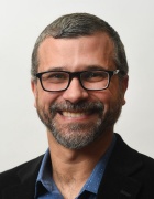 man wearing glasses, smiling. 
