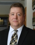 man wearing buisiness suit standing in a library. 