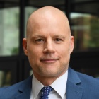 man wearing blue jacket, blue tie, white shirt. 