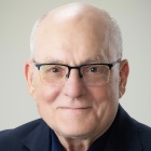 A professional portrait of Errol Meidinger wearing black shirt and glasses. 