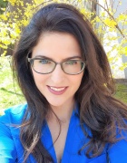 a woman wearing glasses and blue shirt standing outside. 