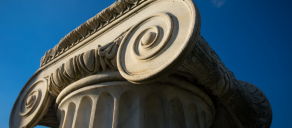 Cover image for the Faculty Scholarship Brochure featuring a close-up of a classical stone column capital against a blue sky.