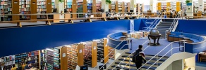 Multi level law library with bookshelves, study tables, and a central staircase connecting reading and research areas.