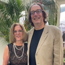 man and woman standing in front of a houseplant. 