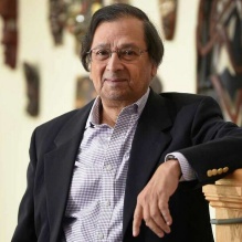 man standing with arm rested on a staircase. 