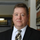 man standing next to bookshelves. 