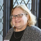 woman wearing glasses, smiling. 