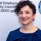 woman smiling, standing in front of a sign that says U.S. Equal Employment Opportunity Commission. 