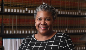 woman smiling, standing in a library. 