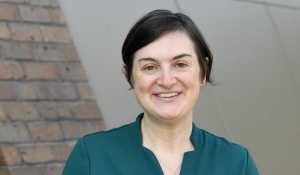 woman smiling, standing outside. 