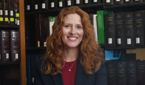 woman smiling, standing in a library. 