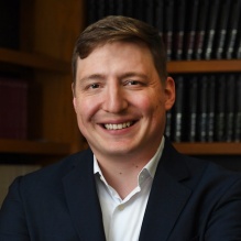 man standing, arms crossed, smiling. 