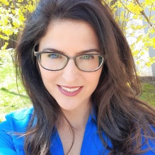 woman wearing glasses, smiling. 