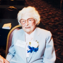 A person wearing a blue ribbon pinned to their light-colored outfit. 