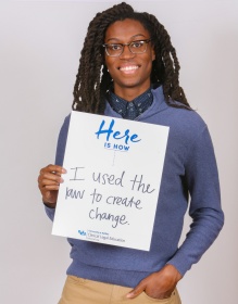 UB Law clinic student holding a sign that says Here is how I used the law to create change. 