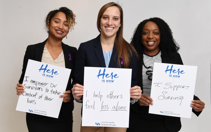 Three clinic students holding signs about family violence. 