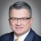 man wearing suit, tie and glasses.