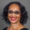 Woman wearing black top, glasses, smiling.