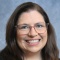 Professional portrait of Lisa Bauer wearing black blazer and glasses. 