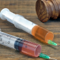 photo of two syringes and a judges gavel. 