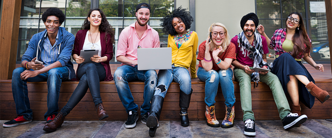 photo of a diverse group of students sitting next to each other and smiling. 