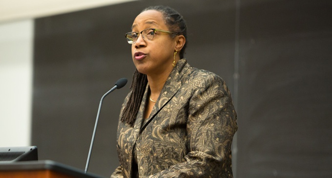 Miller speaking at a podium. 