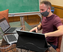 Law student Stephen Soos surrounded by laptop computers on a desk. 