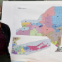 law student standing in front of a redistricting map of new york state. 