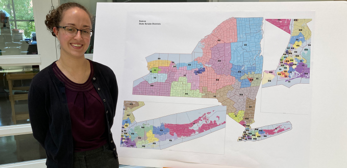 student standing in front of a map of new york state. 