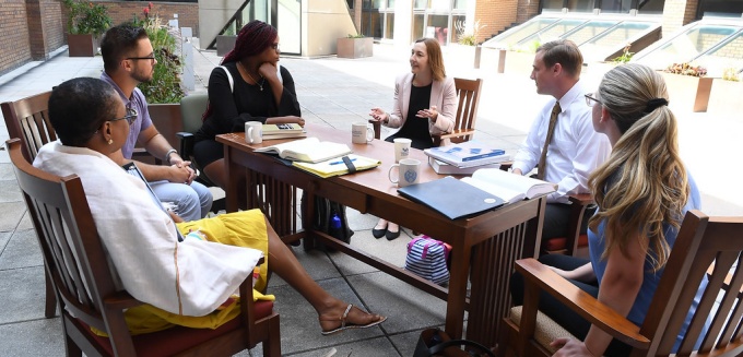 Professor Abraham sitting at a table outside with students. 
