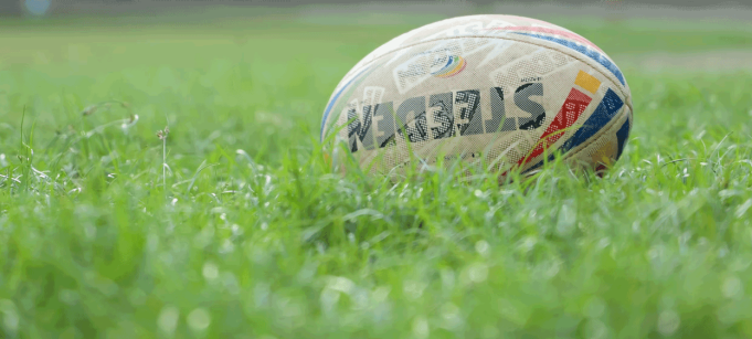 photo of a rugby football sitting in a field. 