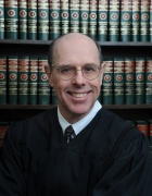 Fahey standing in front of a book shelf that is full of legal books. 