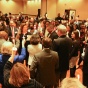 people gathered a dimly lit room, holding candles. 