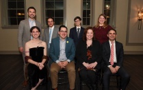 group of dinner attendees siting and standing for a photo. 